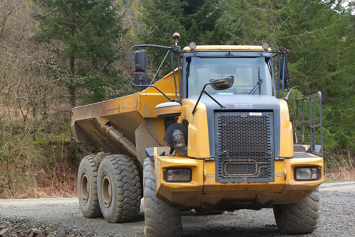 Camion benne articulé chargé de terre roulant sur une piste de chantier